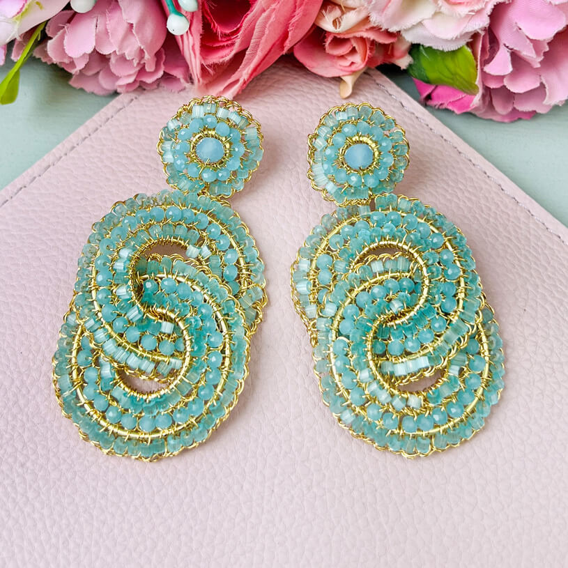 Vergoldete Ohrstecker aus verschlungenen türkisfarbenen Perlenringen