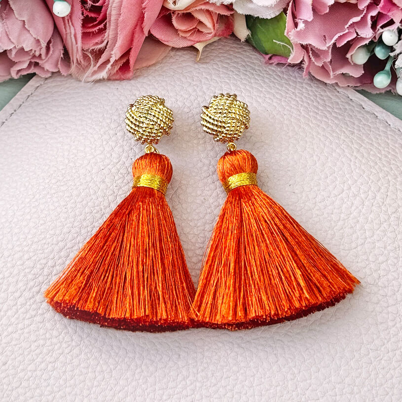 Vergoldete Knoten-Ohrstecker mit oranger Quaste