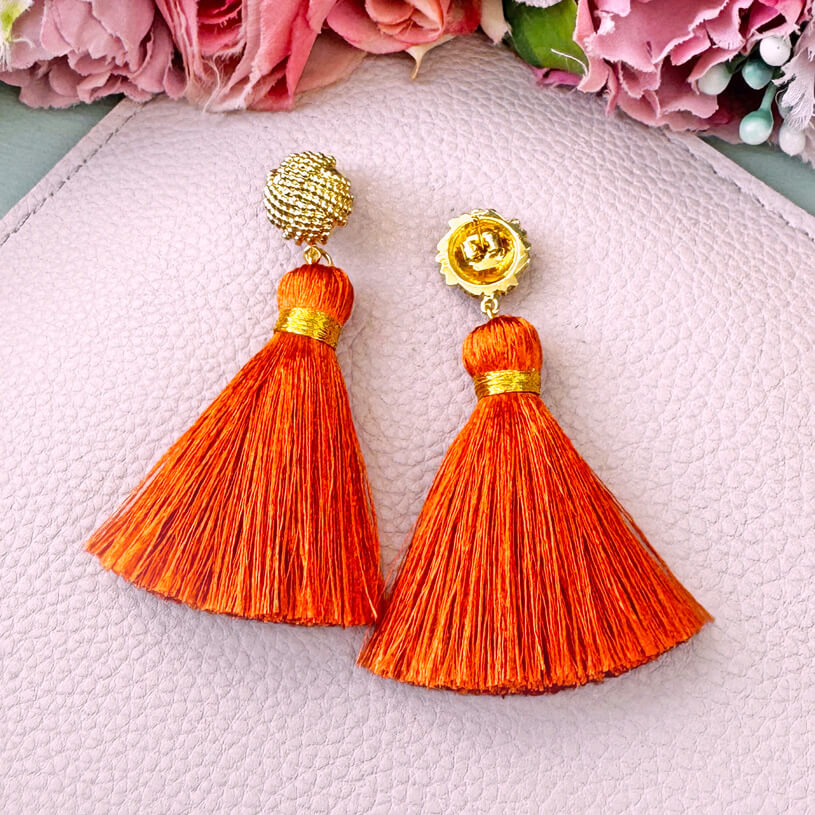 Vergoldete Knoten-Ohrstecker mit oranger Quaste