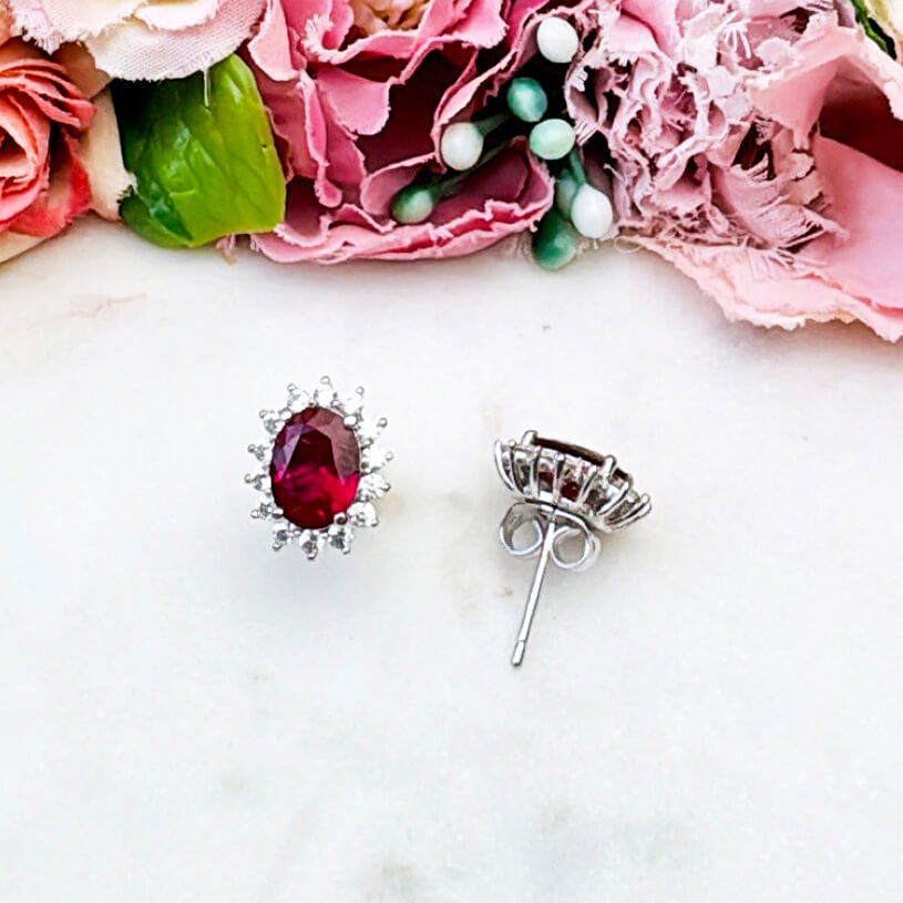 Strahlende silberfarbene Ohrstecker mit ovalem Kristall in Rot