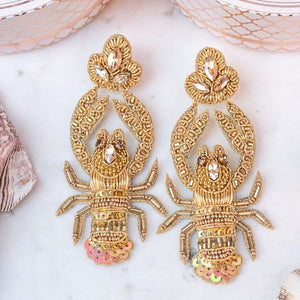 Auffällige Soutache-Ohrringe als goldfarbener Hummer