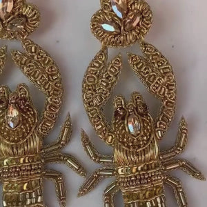 Auffällige Soutache-Ohrringe als goldfarbener Hummer